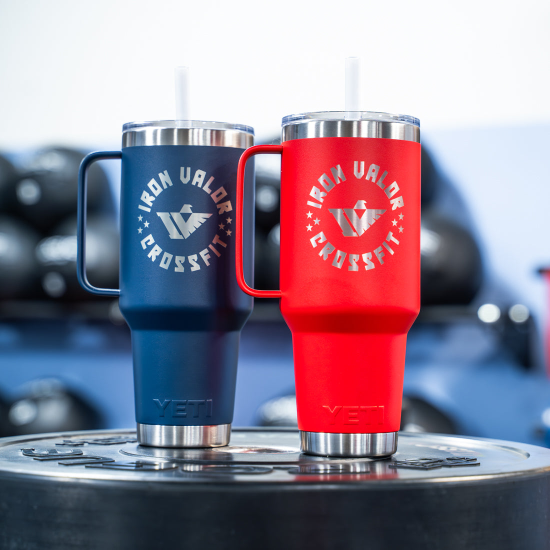Two YETI tumblers, one blue and one red, with Iron Valor CrossFit logo on a blurred background.