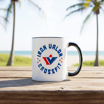 White mug with Iron Valor CrossFit logo on a wooden surface with palm trees and ocean in the background